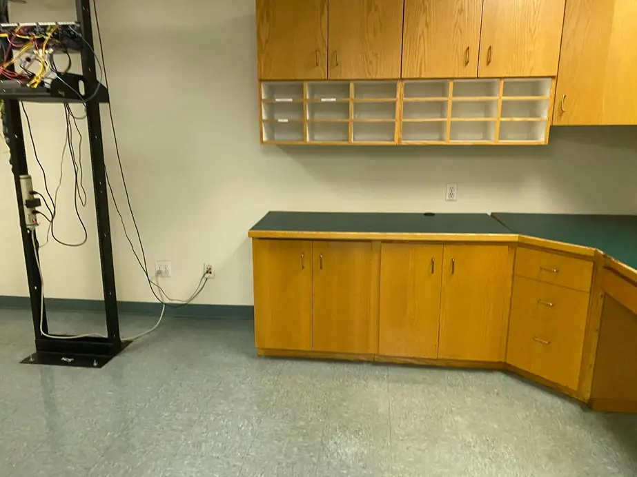 An empty office with built-in cabinetry and a network rack